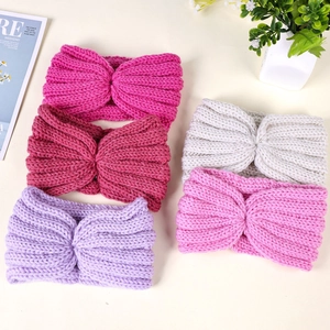 Detailed view of assorted knitted headbands in five soft colors with crossover knot design