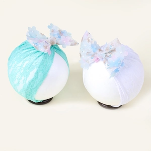 Détail de bandeaux bébé en dentelle avec grands nœuds en tulle, fleurs et paillettes