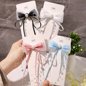 Detail von vier bunten Haarklammern mit Organza-Schleifen und Perlenquasten auf Display
