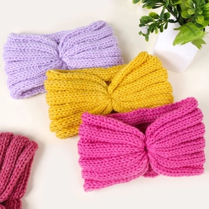 Close-up of knit twisted headbands in purple, yellow, and red with warm woolen texture