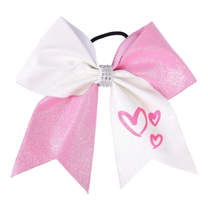 Detail of pink and white glitter bow hair tie with rhinestone center and heart patterns