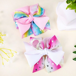Detail of large rainbow ribbon bow hair clips with silver heart patterns on fabric