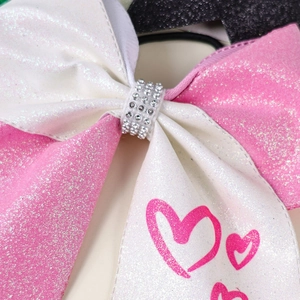 Detail of pink and white glitter hair bow with silver rhinestones and heart pattern