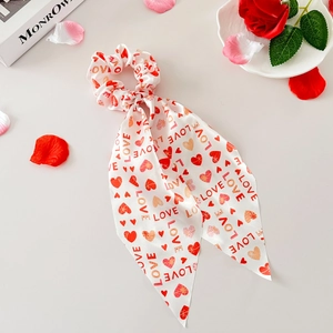 Détail du chouchou en satin crème avec cœurs rouges et imprimé LOVE et pétales
