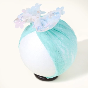 Détail du bandeau en dentelle vert menthe pour bébé avec nœud à paillettes