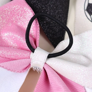 Close-up of sequin bow hair tie with rhinestone center and pink black fabric textures