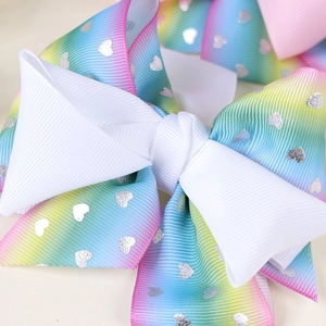 Detail of multi-layered bow hair clip with white ribbon and rainbow gradient heart pattern