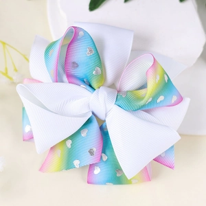Detail of white grosgrain ribbon hair bow with rainbow gradient edges and silver hearts