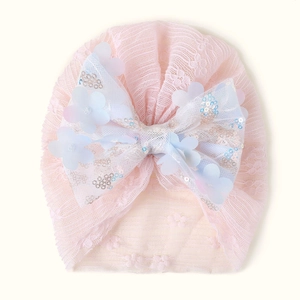 Détail du bonnet turban rose pour bébé avec dentelle, nœud à paillettes et fleur