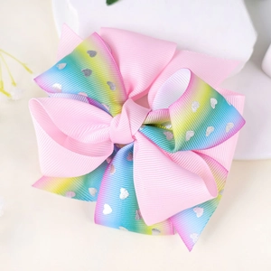 Close-up of rainbow gradient bow hair clip with silver heart glitter patterns