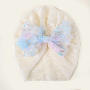 Détail du turban en dentelle pour bébé avec fleurs en résille et paillettes argentées