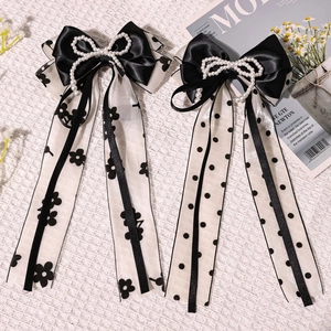 Détail de nœuds élégants en satin noir et mousseline avec perles sur tissu texturé