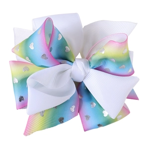 Close-up of rainbow gradient bow hair clip with silver heart patterns and grosgrain texture