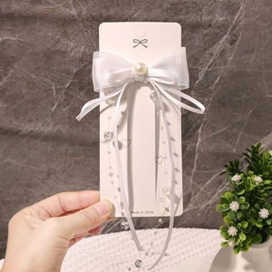 Makroaufnahme einer weißen Schleifen-Haarspange mit langen Bändern, Organza und Kunstperle