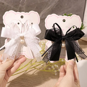 Detail of lace bow hair clips with pearls on handmade card packaging for girls
