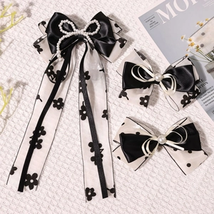 Détail de nœuds papillon noirs avec perles et organza floral sur un tissu blanc