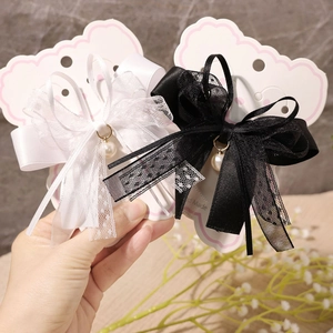 Detail view of lace bow hair clips with elegant pearl charms on a handmade display card