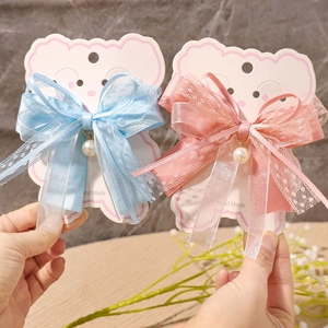 Detailed view of handmade lace and silk bow hair clips with faux pearl pendant charms