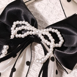 Gros plan d'un nœud en satin noir avec tulle à pois et perles décoratives