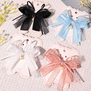 Detail of four handmade lace bow hair clips with pearls and ribbons on card