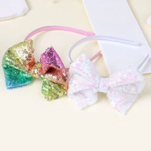 Dettaglio di due cerchietti con fiocchi di paillettes in stile arcobaleno e bianco puro