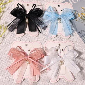 Detail view of lace bow hair clips with faux pearl charms and gold ring accents