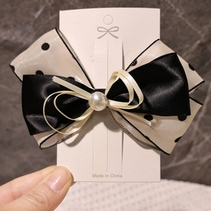 Vue détaillée du nœud papillon multicouche noir et blanc à pois avec une perle