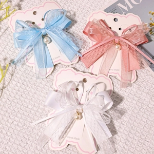 Detailed set of three handmade lace bow hair clips with pearls on a card