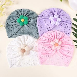 Detail of four breathable eyelet baby turban hats with floral accents in soft pastel colors