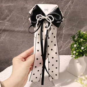 Détail du nœud papillon en satin noir élégant avec perles et rubans à pois classiques