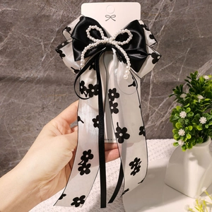 Détail d'un nœud papillon en satin noir avec rubans en mousseline et perles