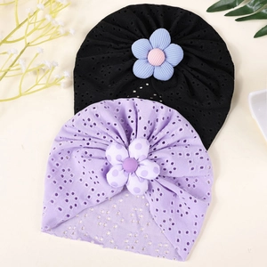 Detail of two breathable baby turban hats with decorative fabric flowers and hollow pattern