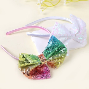 Dettaglio di cerchietti con fiocchi di paillettes rosa e bianchi per capelli bimba