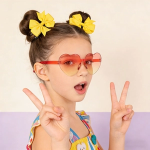 Close-up of child wearing heart-shaped gradient sunglasses and yellow bow hair clips