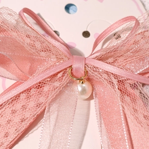 Close-up of pink lace bow hair clip featuring a white pearl pendant and gold metal ring