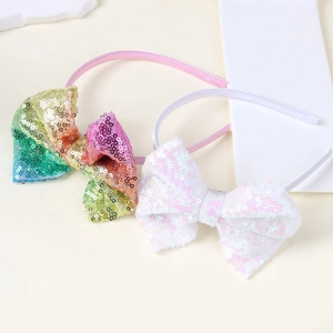 Dettaglio di fiocchi con paillettes arcobaleno e bianche su cerchietti per capelli da bimba