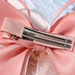 Detail of pink bow hair clip with layered ribbon texture, pearl pendant and metal clip
