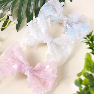 Detailed view of handmade sequined bow hair clips with soft mesh and floral accents
