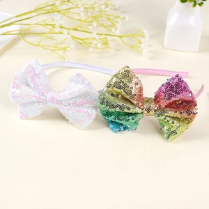 Dettaglio di due cerchietti con fiocchi di paillettes in bianco e colori arcobaleno