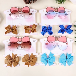Detail of kids heart sunglasses set with matching grosgrain bow hair clips in four colors