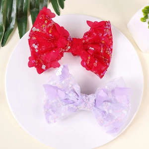 Red and lavender sequined bow hair clips for girls on a decorative ceramic plate