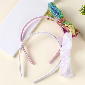 Dettaglio di cerchietti con fiocchi di paillettes rosa e bianchi su vassoio