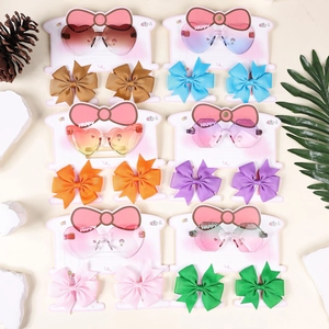 Flat lay of kids sunglasses and bow hair clips set on natural decor background
