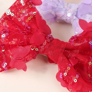 Close-up of red sequined bow hair clip with lace texture and shimmering butterfly detail