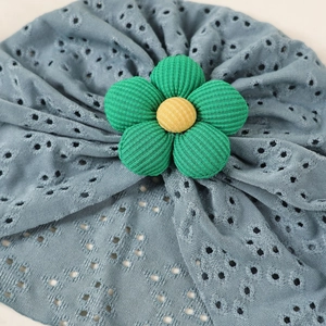 Detailed close-up of breathable hollow-out knit baby hat with a 3D green floral accent