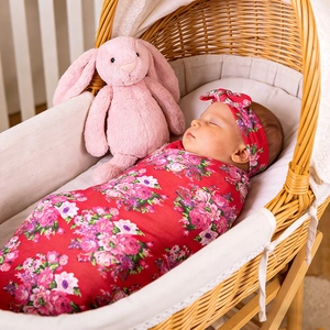 Ensemble lange floral pour bébé avec bandeau assorti présenté sur un nourrisson au lit