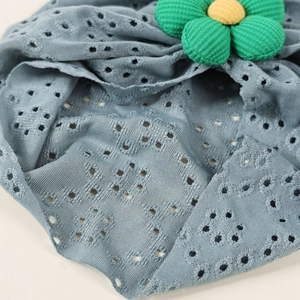 Detailed view of hollow knit baby hat fabric with a soft fabric flower accent