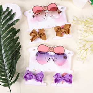 Detail view of kids heart gradient sunglasses and bow hair clips set on pink card