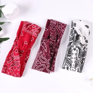 Trois bandeaux à imprimé paisley noués en rouge et blanc sur un fond blanc épuré