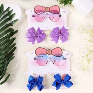 Close-up of heart-shaped gradient sunglasses and bow clips on decorative display card
